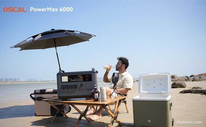 Estación de energía OSCAL PowerMax 6000 en una mesa de playa junto a un hombre, alimentando un ventilador portátil