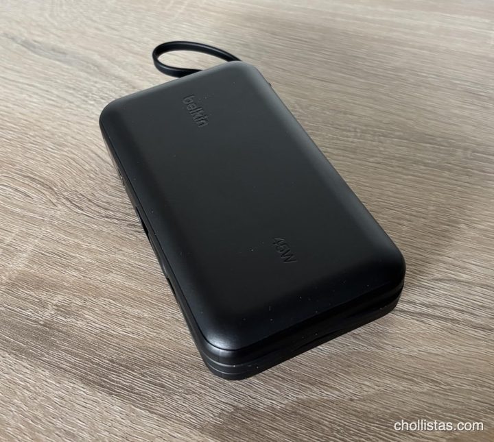 Batería externa Belkin de 45W de color oscuro con cable integrado, sobre una superficie de madera