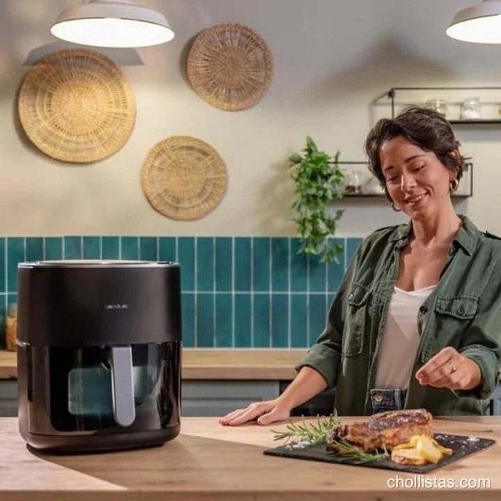 Una mujer sazona un filete de carne recién preparado junto a la freidora de aire Cecotec sobre la encimera